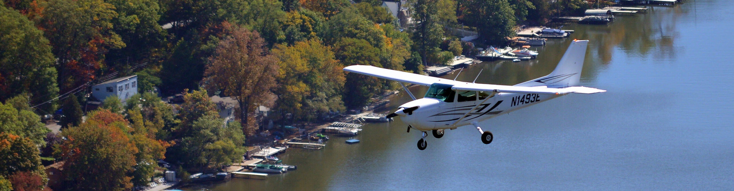 Century Air Cessna flying over lake in Autumn in NJ.