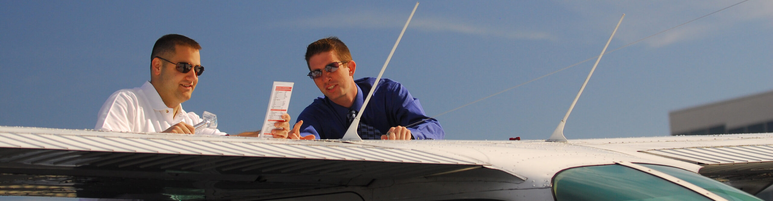 Flight instructor at Century Air talking with student on airplane wing