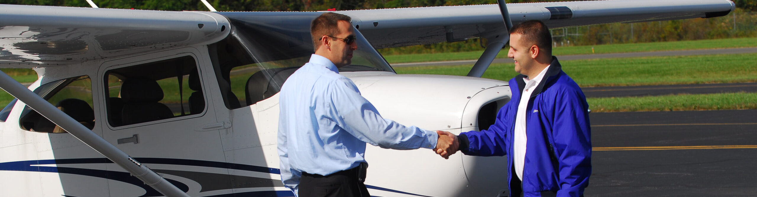 Flight instructor at Century Air Flight School shaking hands with student pilot in front of the aircraft